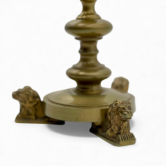 Vintage ornate brass candlestick with lion paw feet and decorative stem.